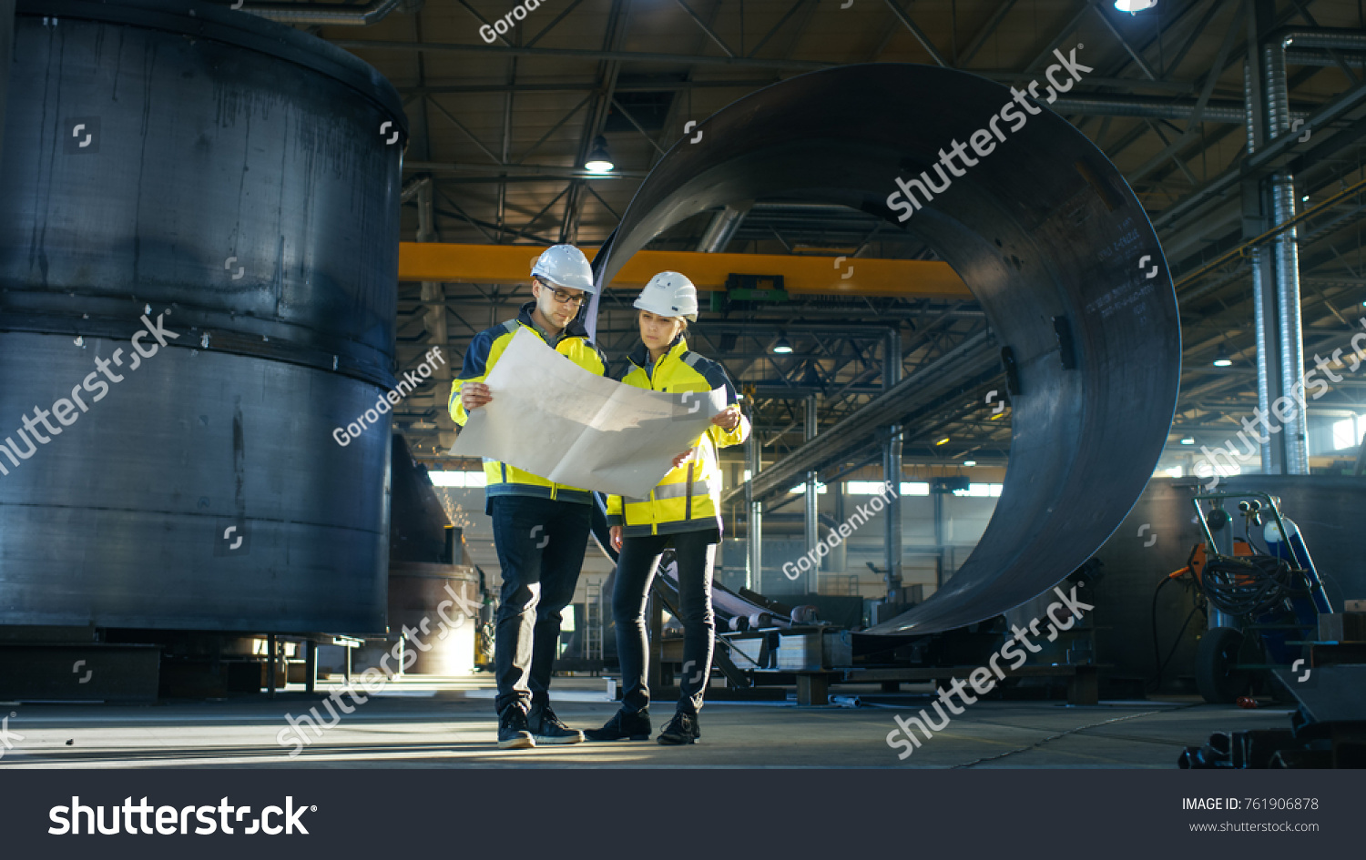 stock-photo-male-and-female-industrial-engineers-look-at-project-blueprints-while-standing-surround-by-pipeline-761906878